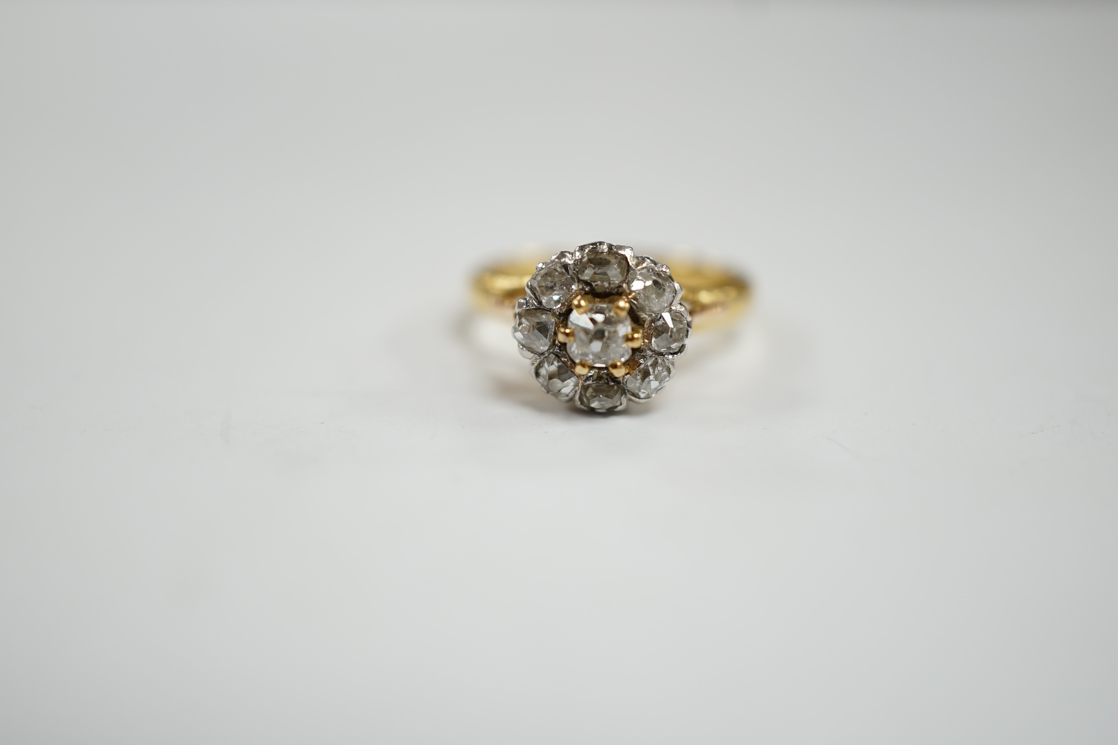An early 20th century French 18k and nine stone diamond set flower head cluster ring, size G, gross weight 3.4 grams.